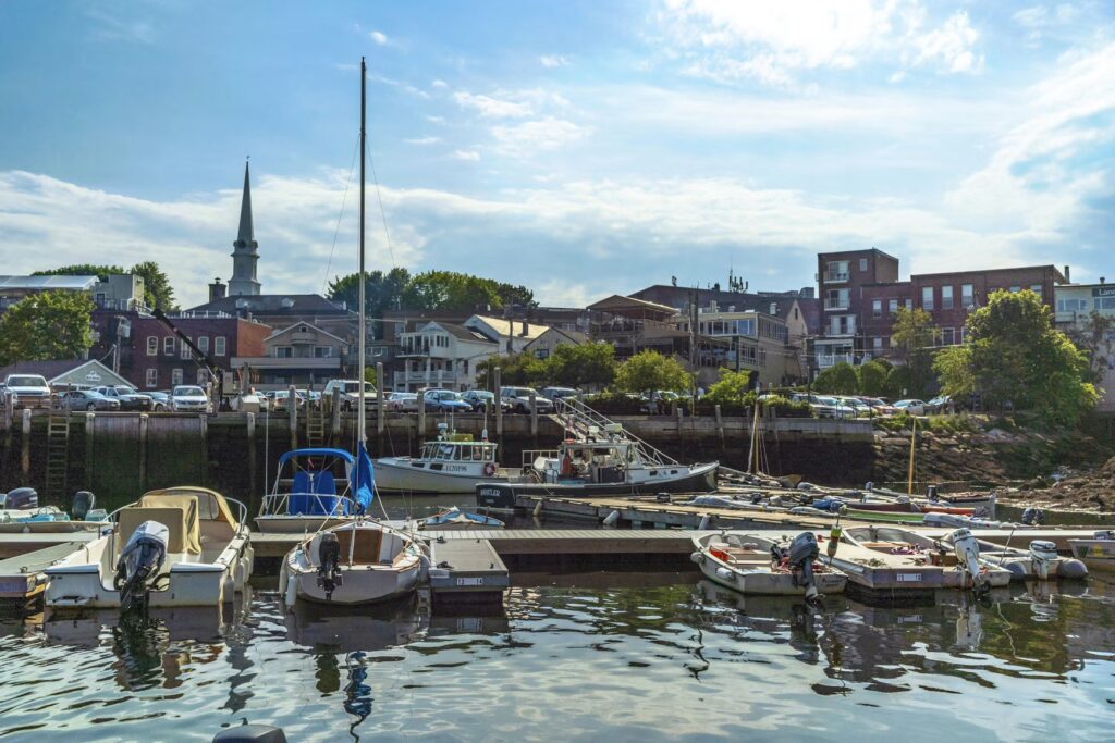 Small boats moored in the scenic harbor with the town skyline of Camden in the background. 