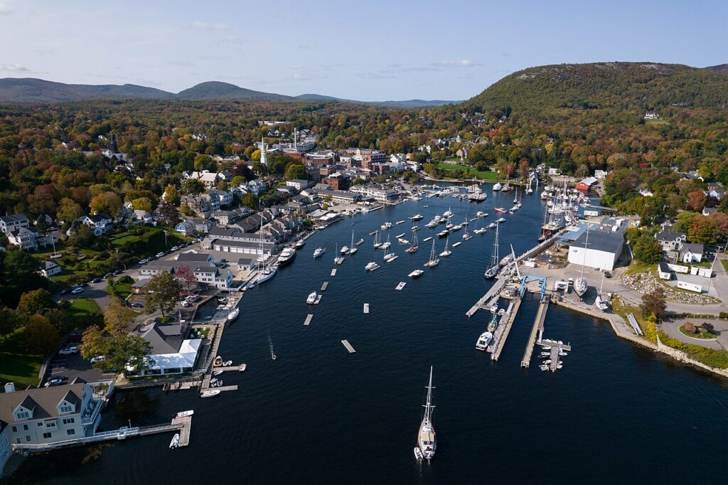 Aerial view of the bustling Camden Harbor filled with moored boats, surrounded by the town and hills.