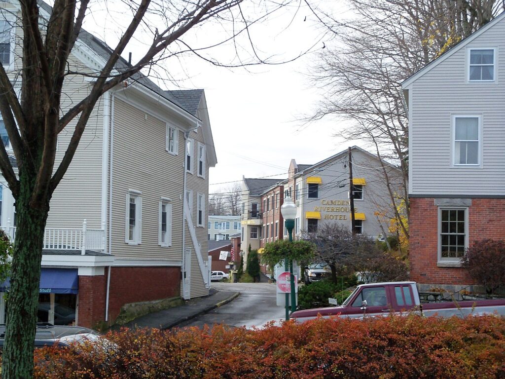 A quiet neighborhood street corner featuring historic homes and the Camden Riverhouse Hotel sign.