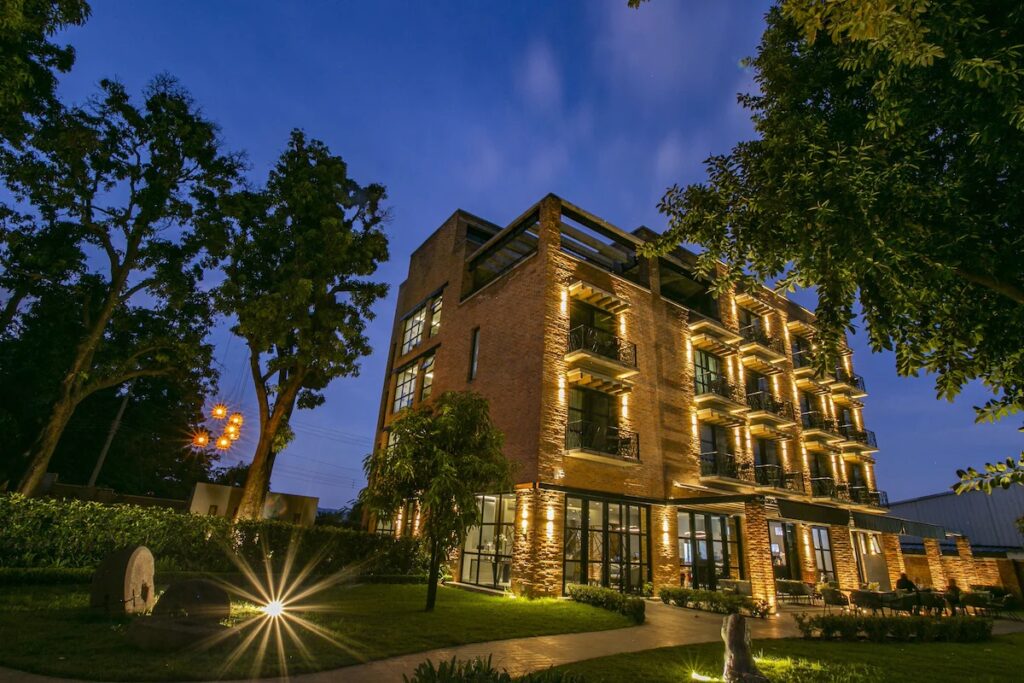The striking brick exterior of Casa Salles Hotel Boutique illuminated against the evening sky in Tequila.