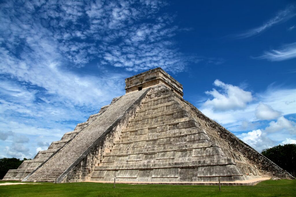 The iconic El Castillo pyramid at Chichén Itzá under a bright blue sky, a popular day trip from Mérida.
