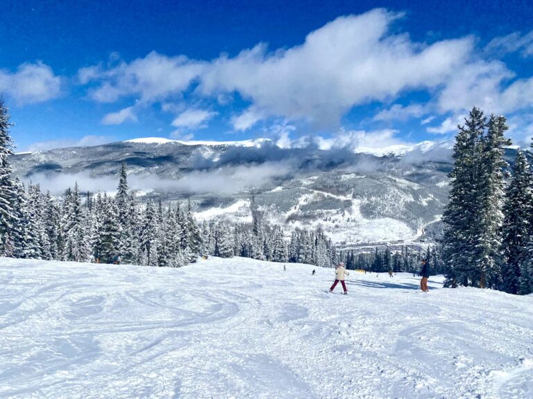 Skiers on a snow-covered mountain slope, enjoying a classic Colorado winter vacation.