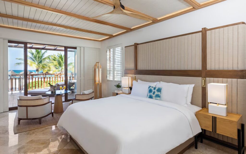 Elegant hotel bedroom featuring a slatted accent wall and large bed at Fairmont Mayakoba. 
