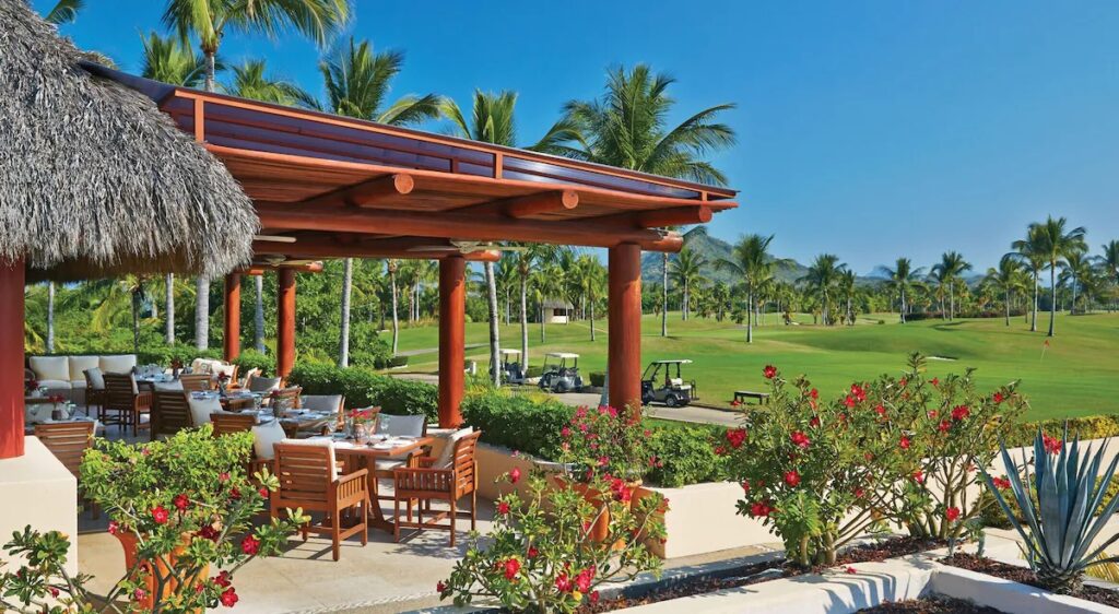 A shaded outdoor dining patio overlooking the pristine manicured golf course at Four Seasons Resort Punta Mita.