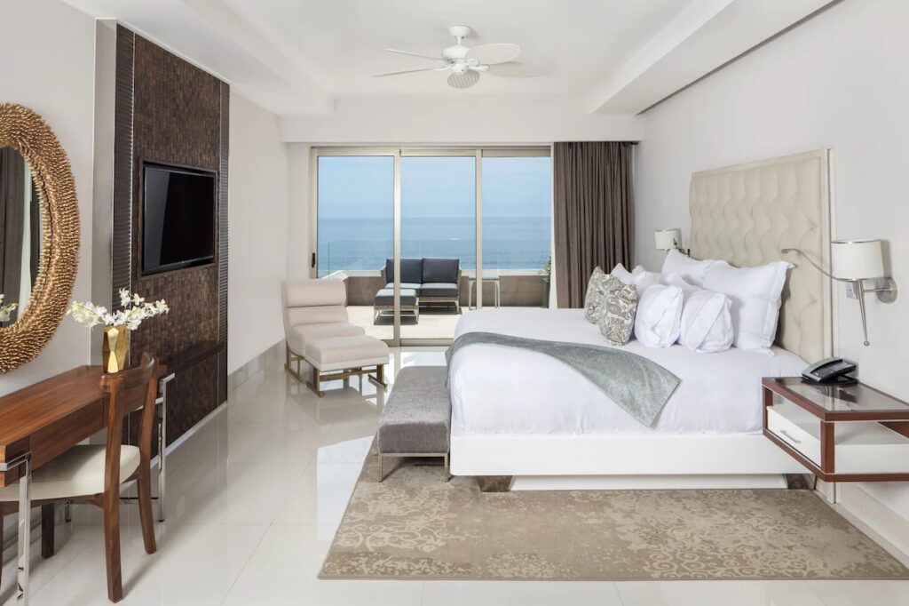 Spacious luxury hotel room with a decorative round mirror at Garza Blanca Resort. 