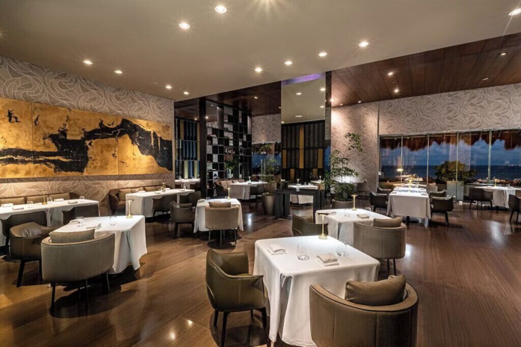 Elegant fine-dining restaurant interior with white tablecloths at Grand Velas Riviera Maya. 