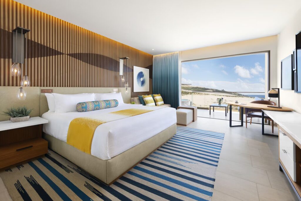 Modern oceanfront suite with a vibrant blue striped rug at Hard Rock Hotel Los Cabos. 