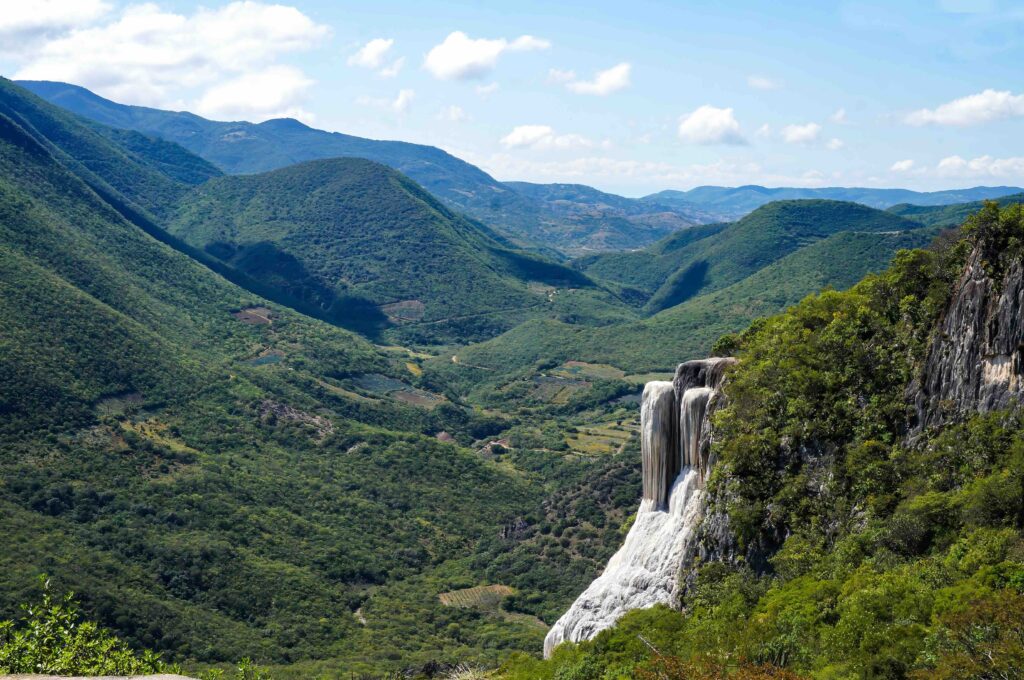 A sweeping view of the dramatic green mountains and the unique mineral formations of Hierve el Agua.