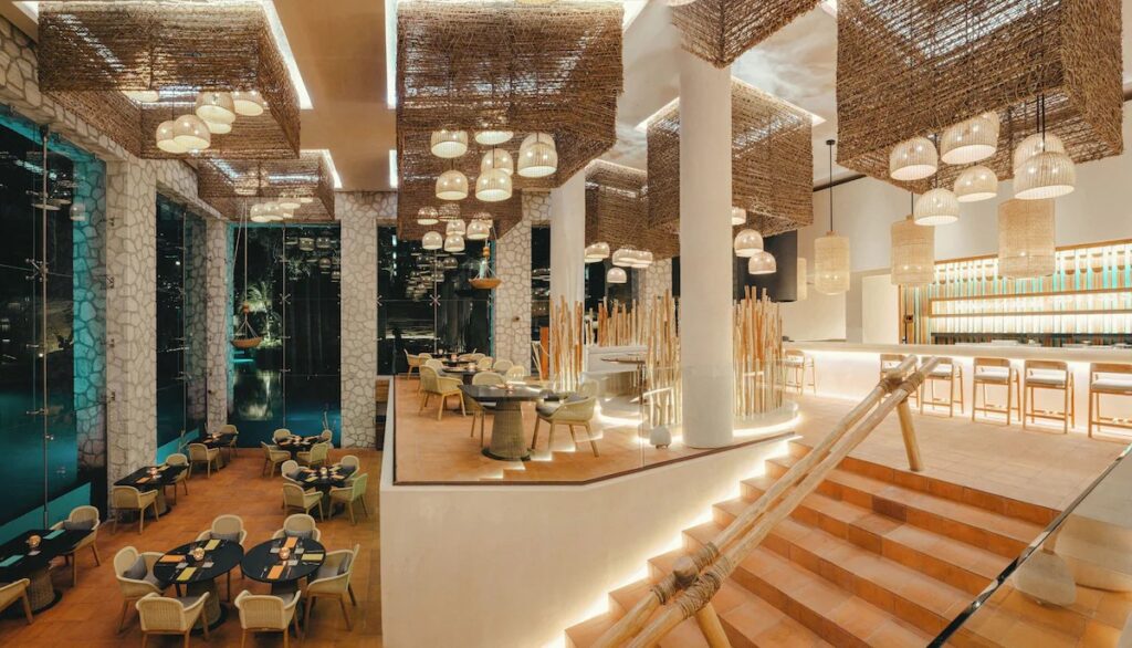 Stylish restaurant interior with large woven hanging lamps at Hotel Xcaret Arte. 