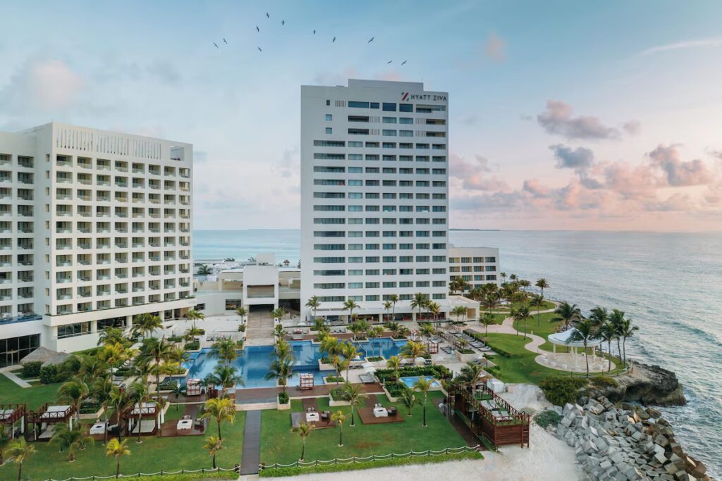 Tall white resort tower overlooking oceanfront pools at Hyatt Ziva Cancun. 