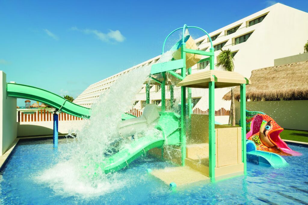 Colorful children's water park area featuring small slides at Hyatt Ziva Cancun. 