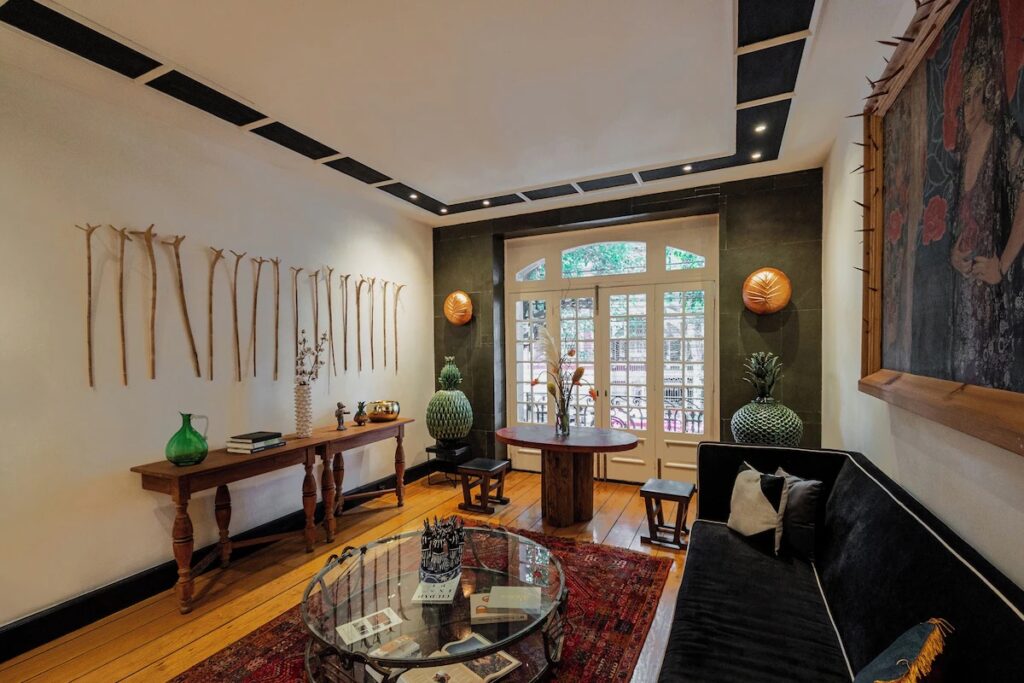 The elegant lobby of La Valise Mexico City, featuring wooden walking sticks mounted on a white wall.