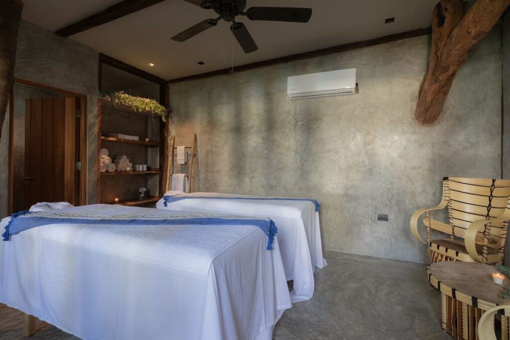 Two massage tables set up in a minimalist, concrete-walled spa treatment room at La Valise Tulum.