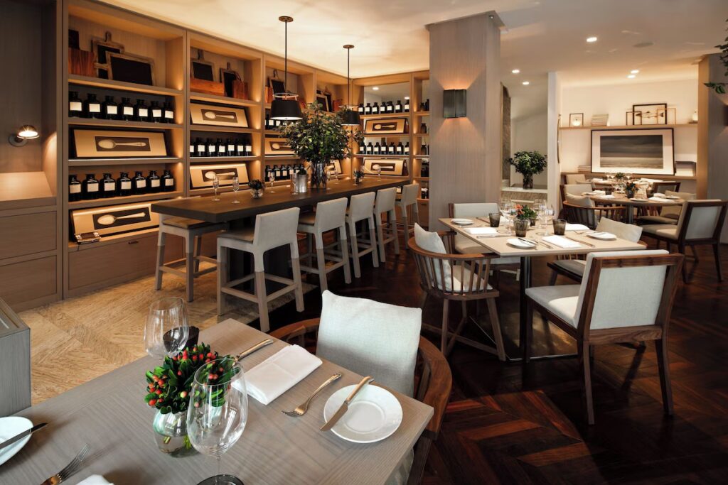 The sophisticated Anatol restaurant interior with wooden tables and a large wine display at Las Alcobas.