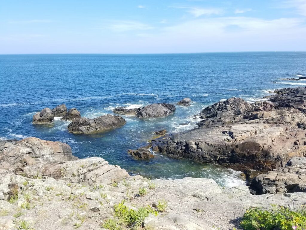 Scenic view of the rugged granite rocks and blue ocean waters seen from the Marginal Way Lighthouse in Ogunquit, Maine.