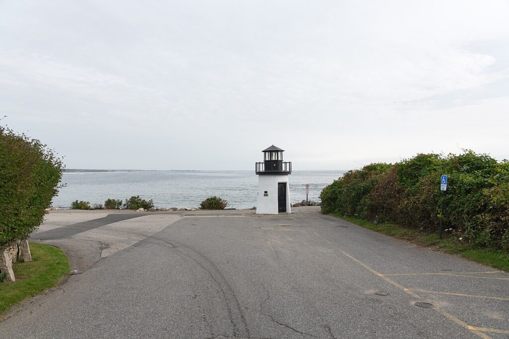 The small, iconic Marginal Way Lighthouse sitting on a paved coastal point in Ogunquit, Maine.