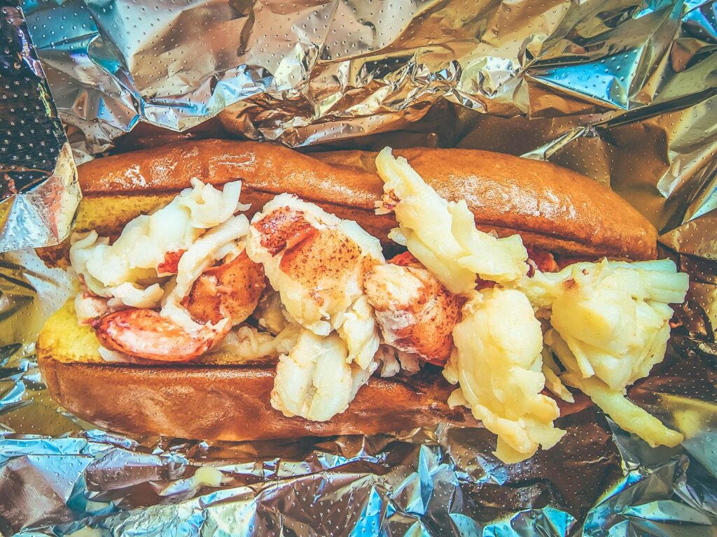 A classic Maine lobster roll piled high with fresh chunks of lobster meat served on a bun.