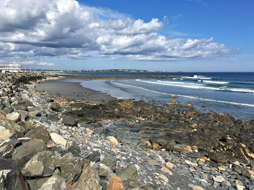 A rocky and sandy shoreline with ocean waves rolling in at Short Sands Beach in York Beach, Maine.