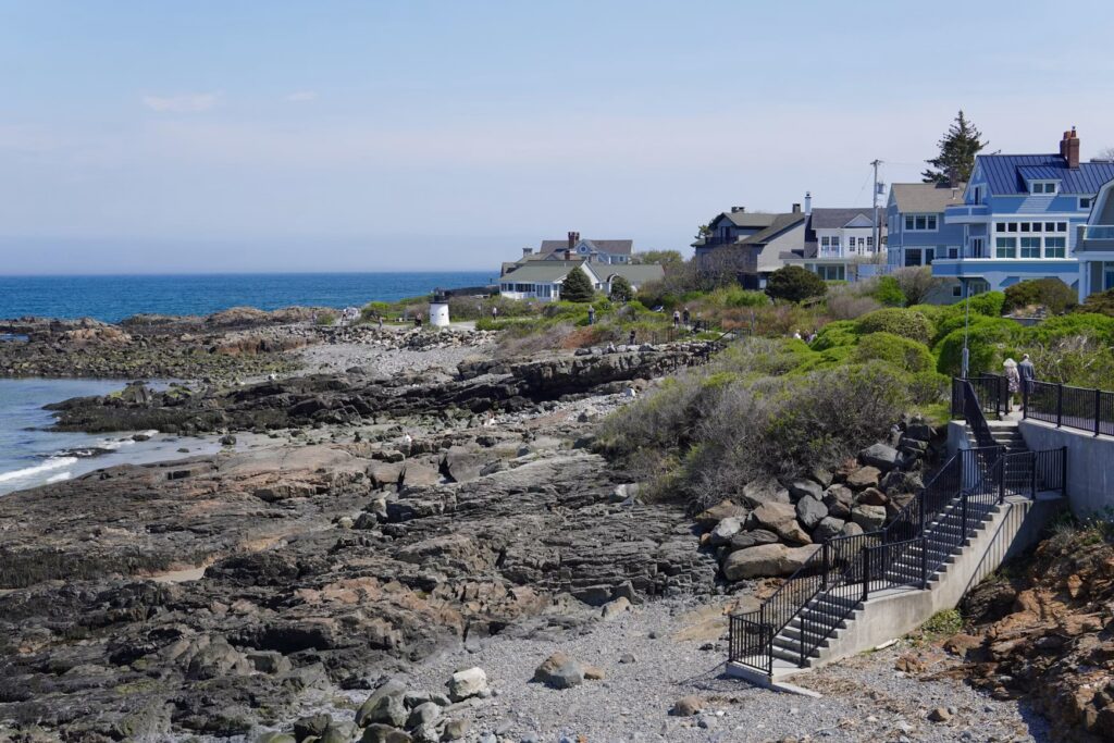 A paved walking path and stairs leading along the rocky oceanfront cliffs of the Marginal Way in Ogunquit, Maine.