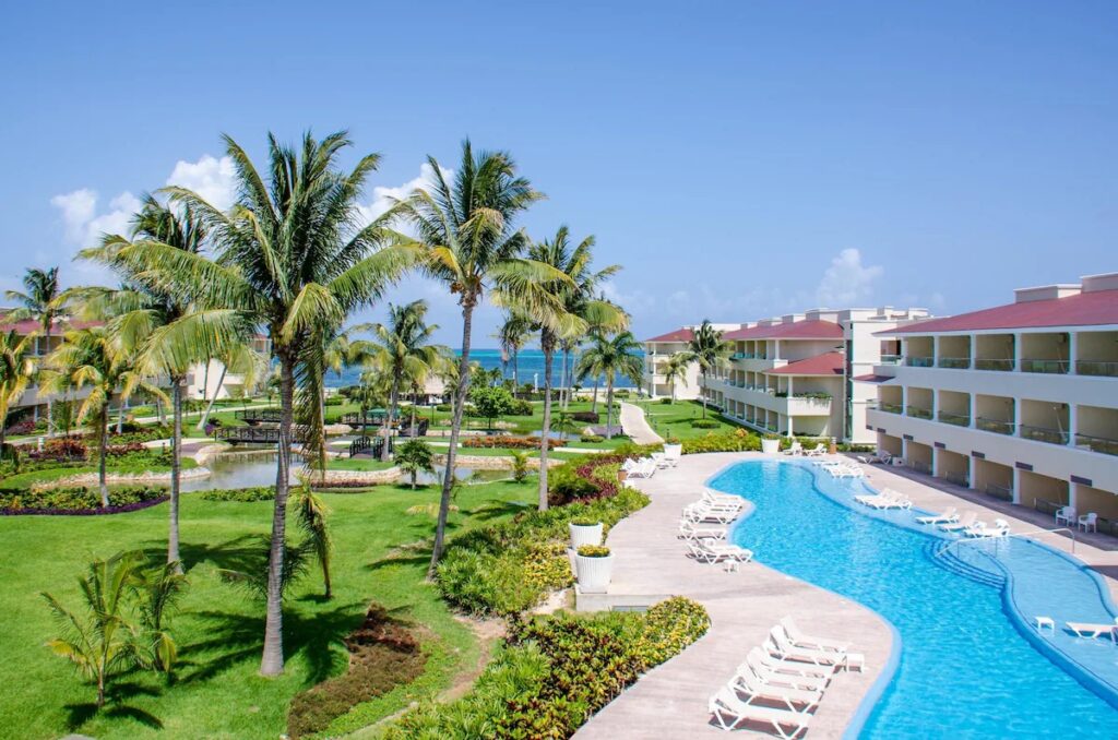 Winding blue resort pool surrounded by palm trees and green lawns at Moon Palace Cancun. 