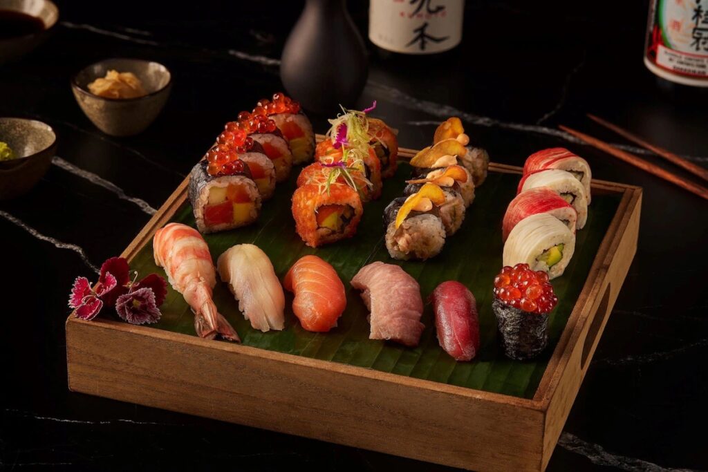 A wooden tray displaying an assortment of gourmet sushi rolls at Moon Palace Cancun. 