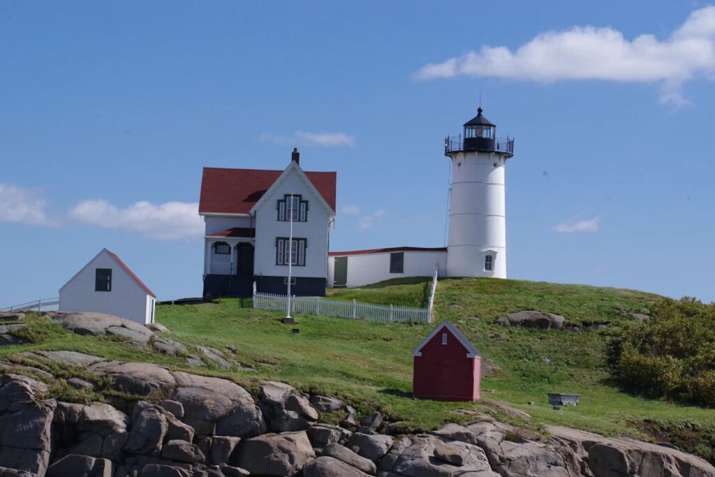 The iconic white tower and red-roofed keeper's house of Nubble Lighthouse on a rocky island in Cape Neddick, York.