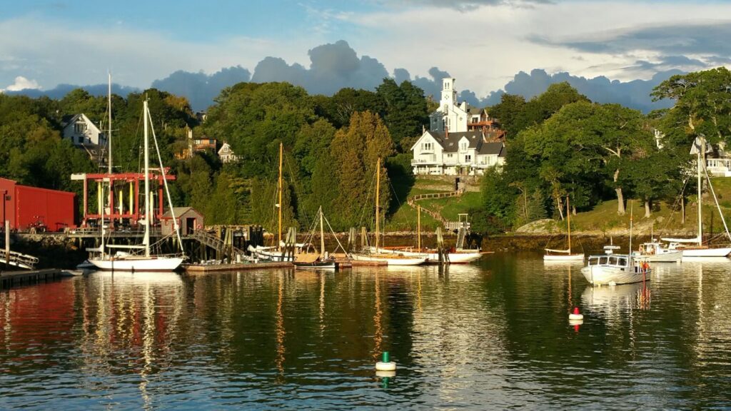 12 Best Things to Do in Ogunquit, Maine (Cliffs, Coves & Itineraries) Scenic harbor with sailboats and white houses reflecting in the water at sunset in Ogunquit, Maine.