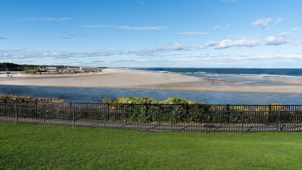 A sweeping view of the sandy Ogunquit Beach peninsula seen from a grassy overlook at the Sparhawk end, Maine.