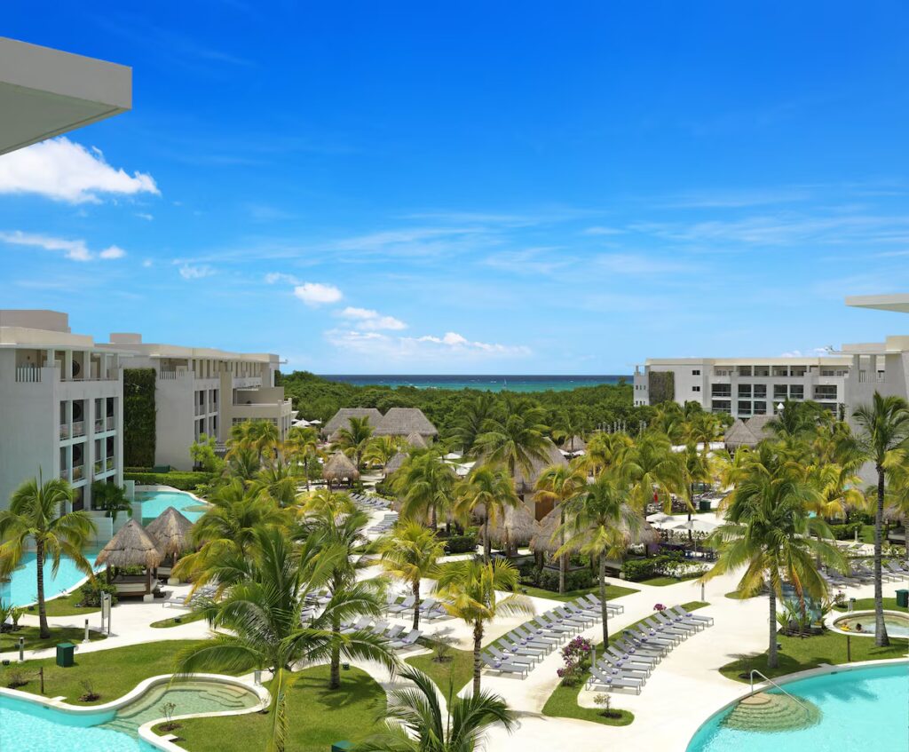 Resort view showing a winding pool and tropical palm trees at Paradisus La Perla. 