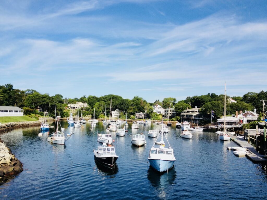 A peaceful view of Perkins Cove in Ogunquit, Maine, filled with numerous moored boats and surrounded by trees.