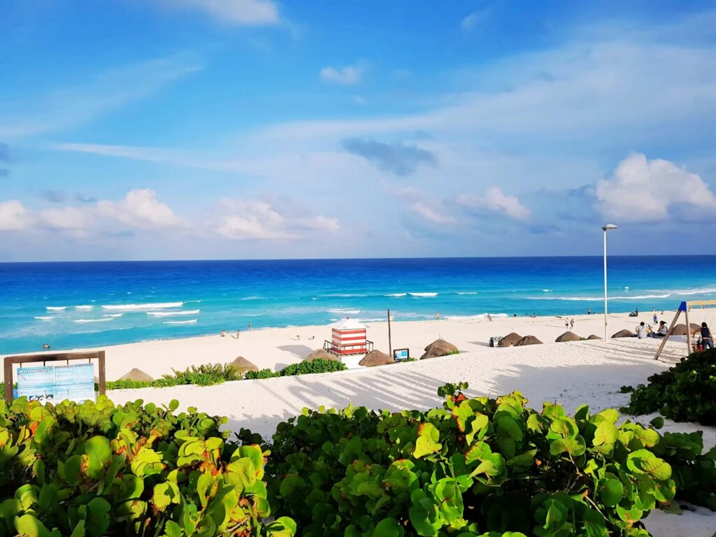 A vibrant view of the turquoise Caribbean Sea and white sand at Playa Delfines, showing why people ask, "is Cancun safe?"