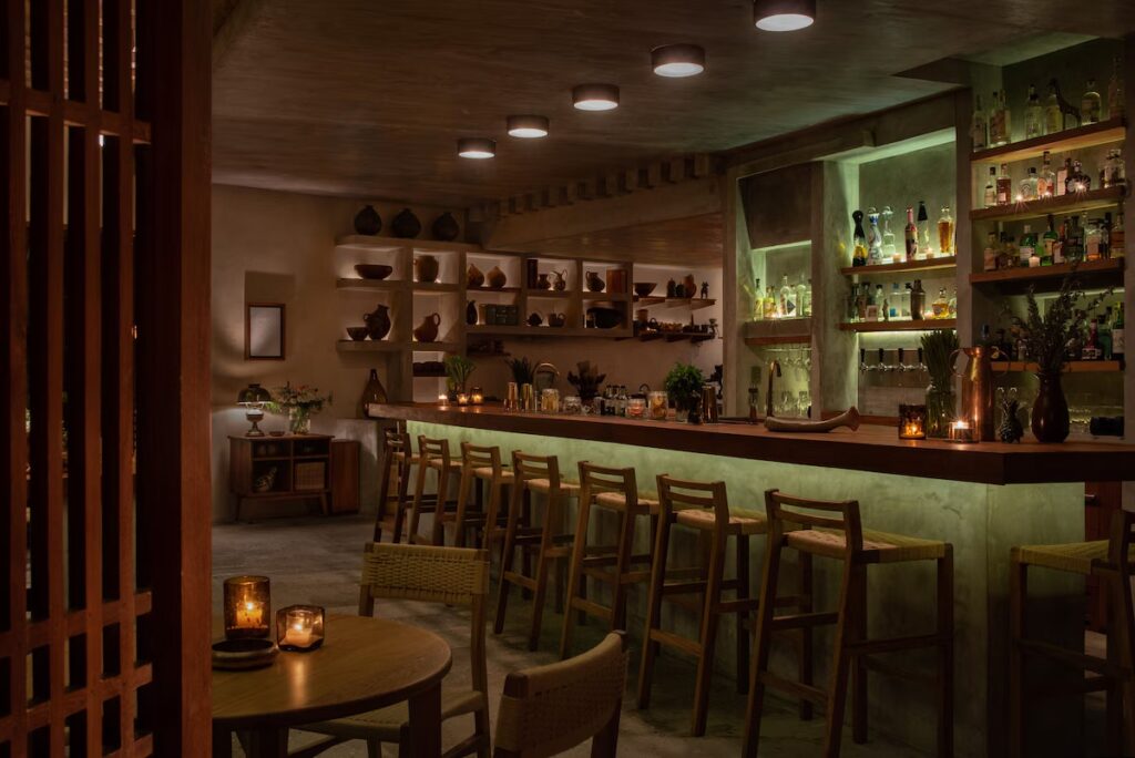The dimly lit, sophisticated interior of Zapote Bar at Rosewood Mayakoba, featuring a premium spirits collection.