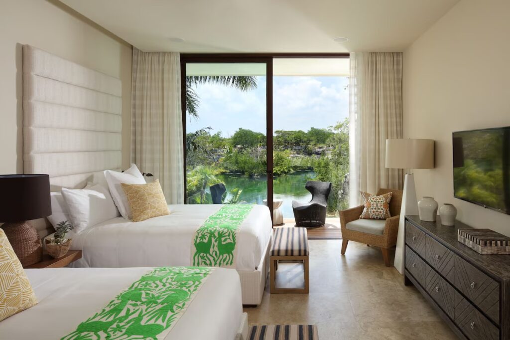 A bright luxury bedroom with sliding doors opening to a private waterfront terrace at Rosewood Mayakoba.