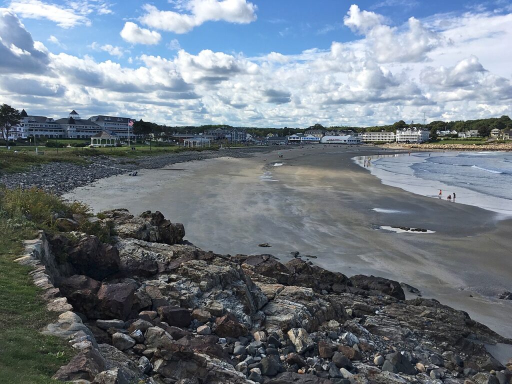 A sweeping view of the wide sandy shoreline and distant buildings at Long Sands Beach in York Beach, Maine.