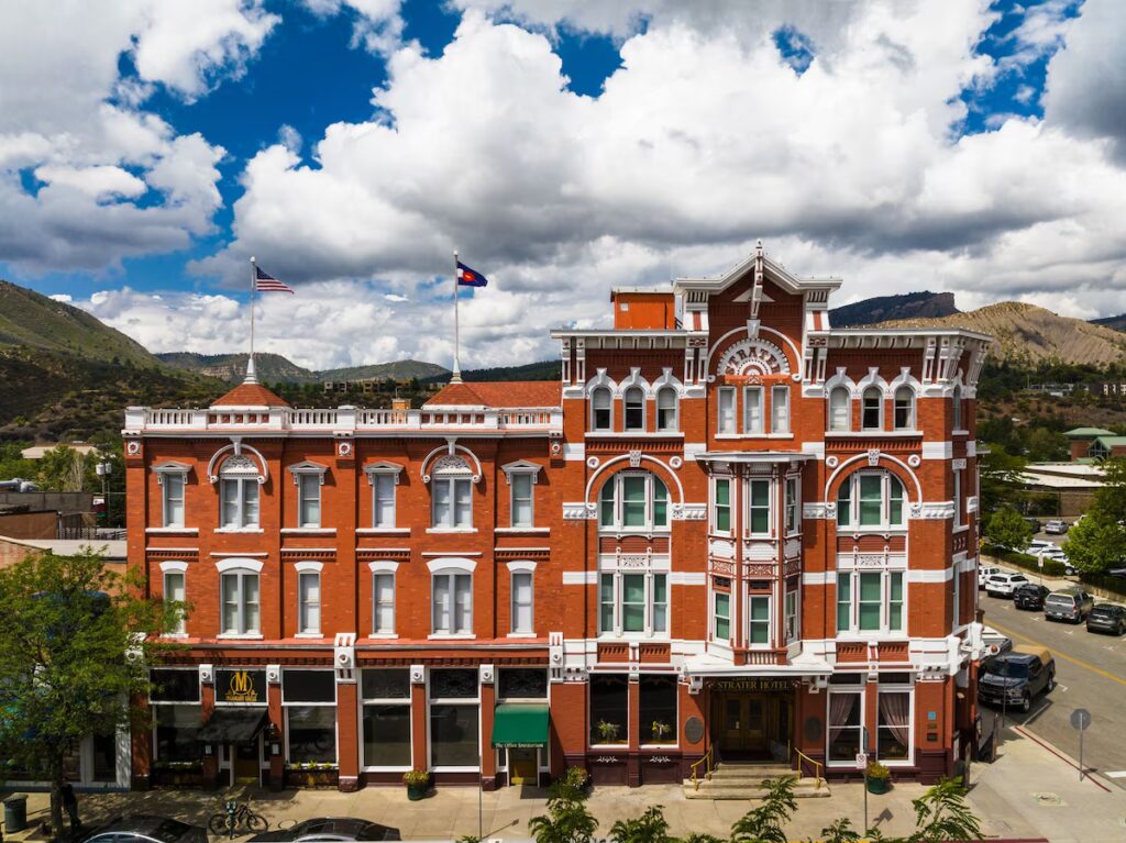 Red brick exterior of the Historic Strater Hotel in Durango on a sunny day. 