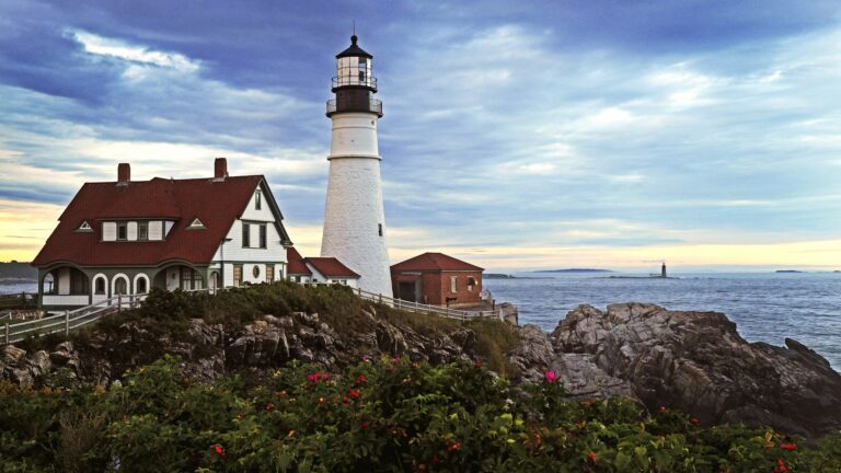 Portland Head Light perched on a rocky cliff against a dramatic cloudy sky, among best things to do in Portland.