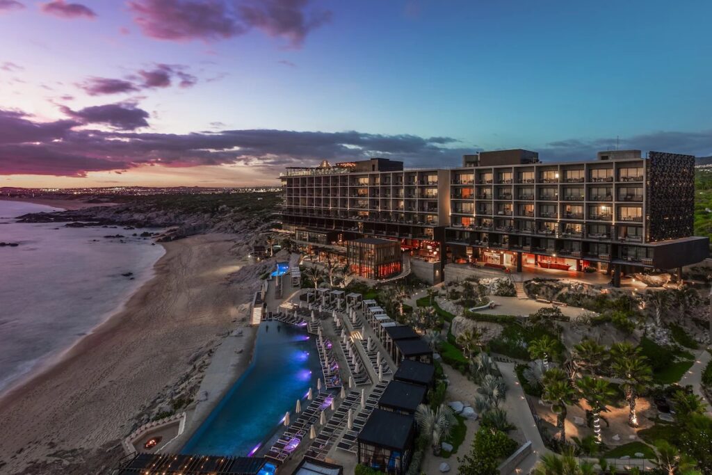 An aerial view of The Cape, A Thompson Hotel, showing its dramatic coastal setting at sunset.