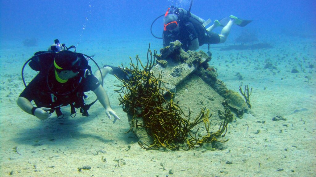 Two scuba divers examining a small underwater structure on the sandy bottom in the US Virgin Islands.