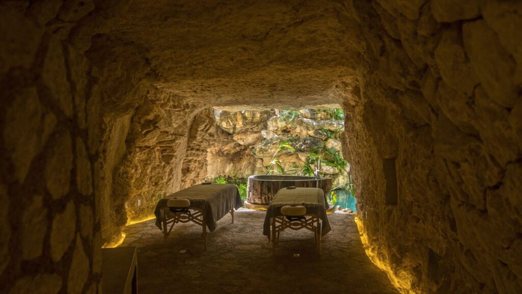 Unique cave spa treatment room with stone walls and a soaking tub at Hotel Xcaret Mexico. 