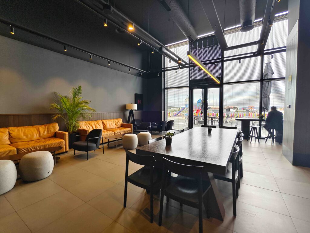 An empty, modern airport lounge with leather couches and a long table.