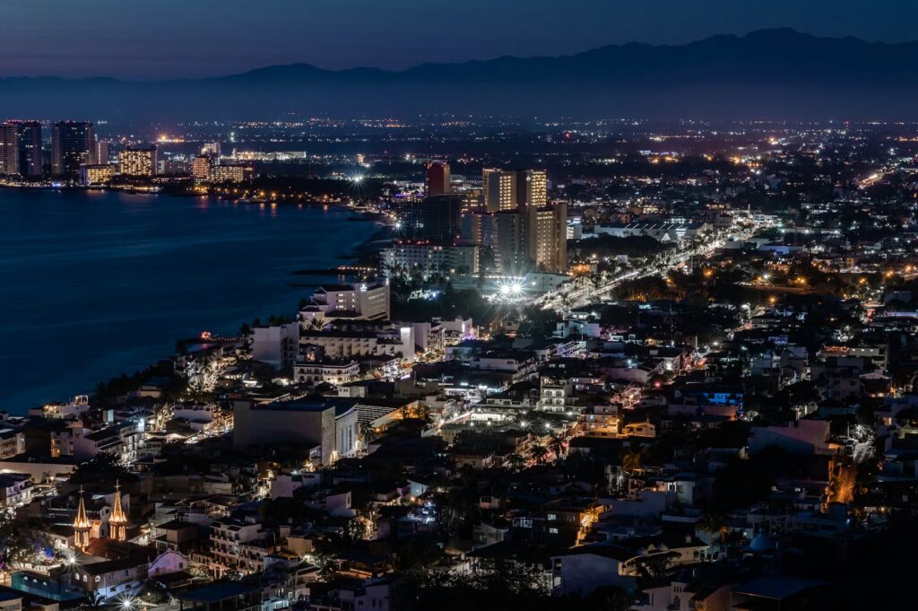 11 Safest Cities in Mexico: A 2026 Worry-Free Guide (+ 3 to Avoid) A night view of the sparkling coastline and city lights of Puerto Vallarta, reflecting one of the safest cities in Mexico.