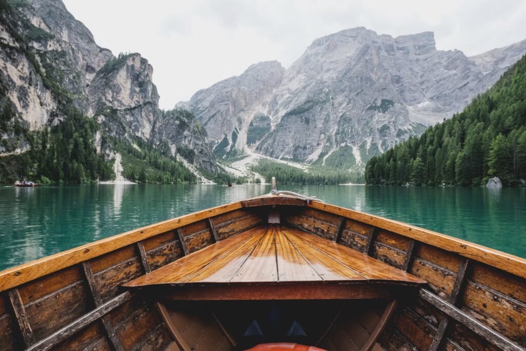 23 Best Travel Hacks for 2026: Pack Lighter & Travel Stress-Free View from a wooden boat on a calm emerald lake surrounded by rocky mountains.