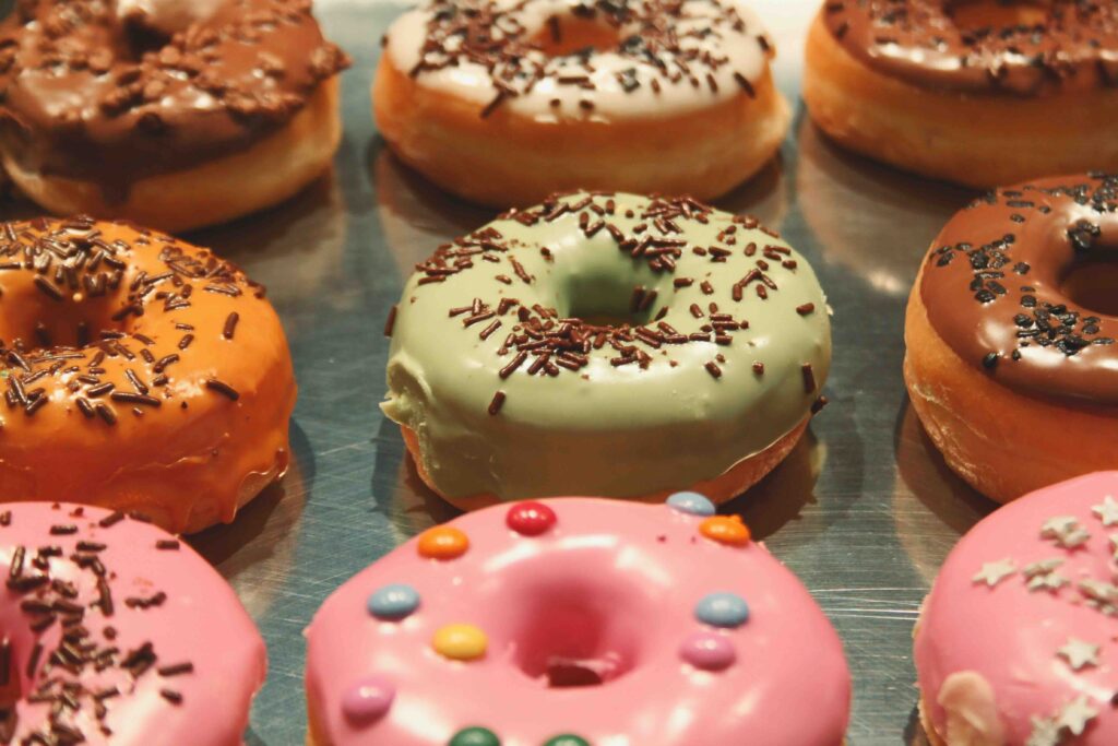An assortment of colorful and uniquely flavored potato donuts arranged neatly on a metal tray. 