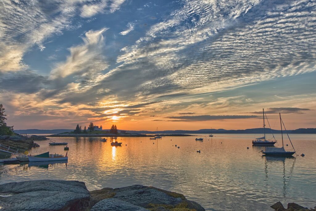 25 Best Things to Do in Maine (Must-Do Activities & Hidden Gems) Stunning sunset over a peaceful harbor and lighthouse, perfect for discovering the best things to do in Maine.