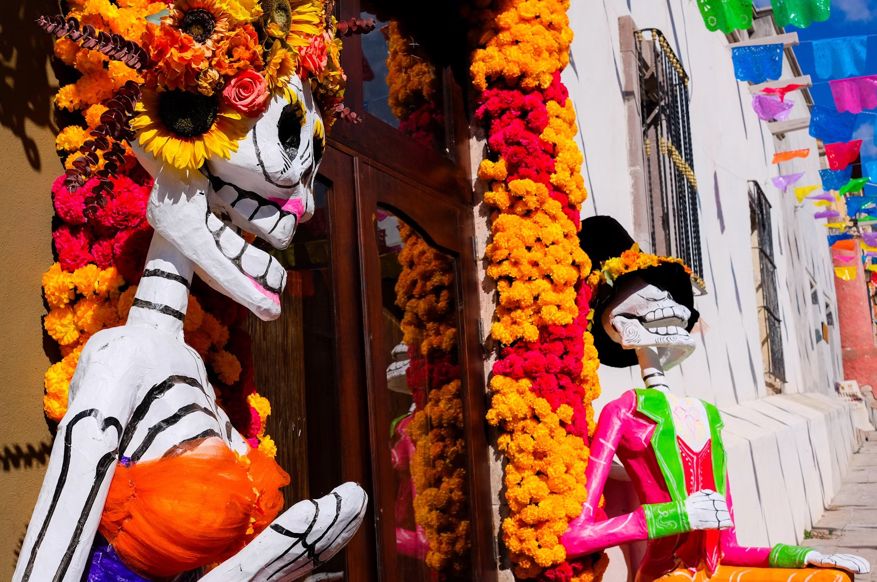 Skeletal figures decorated with marigolds in Mexico, illustrating why autumn is the best time to visit Mexico. 