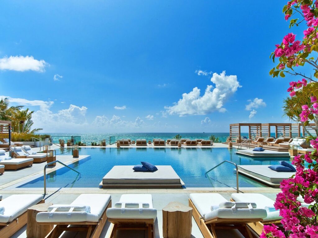 A luxurious infinity pool surrounded by lounge chairs and pink bougainvillea, an iconic feature among resorts in Florida.