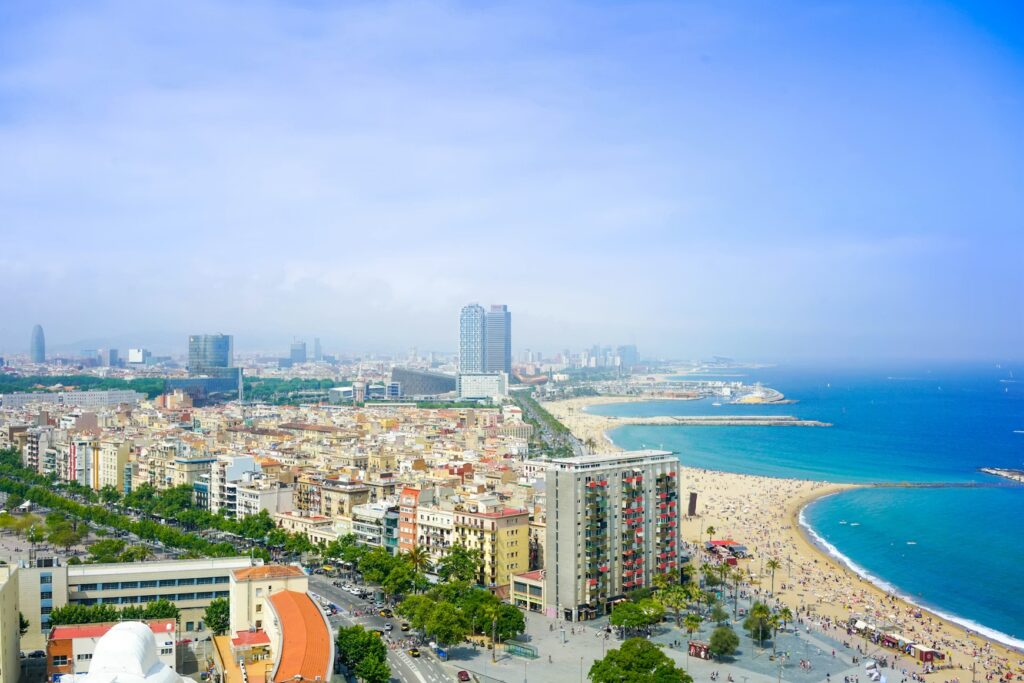 A wide, curved sandy beach next to a vibrant urban skyline in Barcelona.