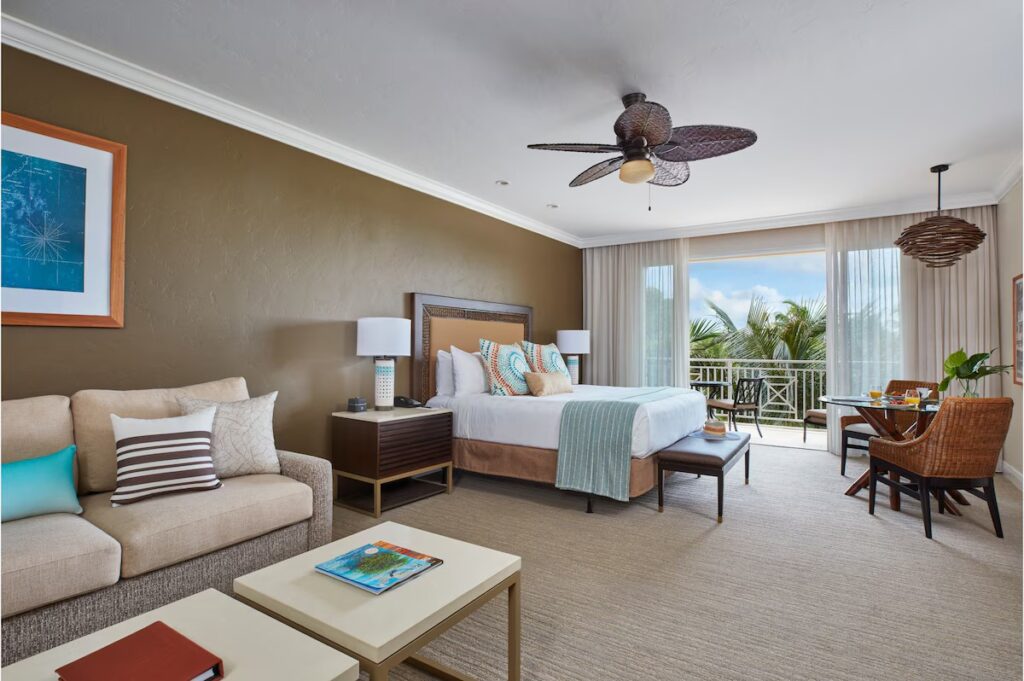 A tropical-style room at Cheeca Lodge & Spa with a king bed, a seating area, a ceiling fan, and a balcony.