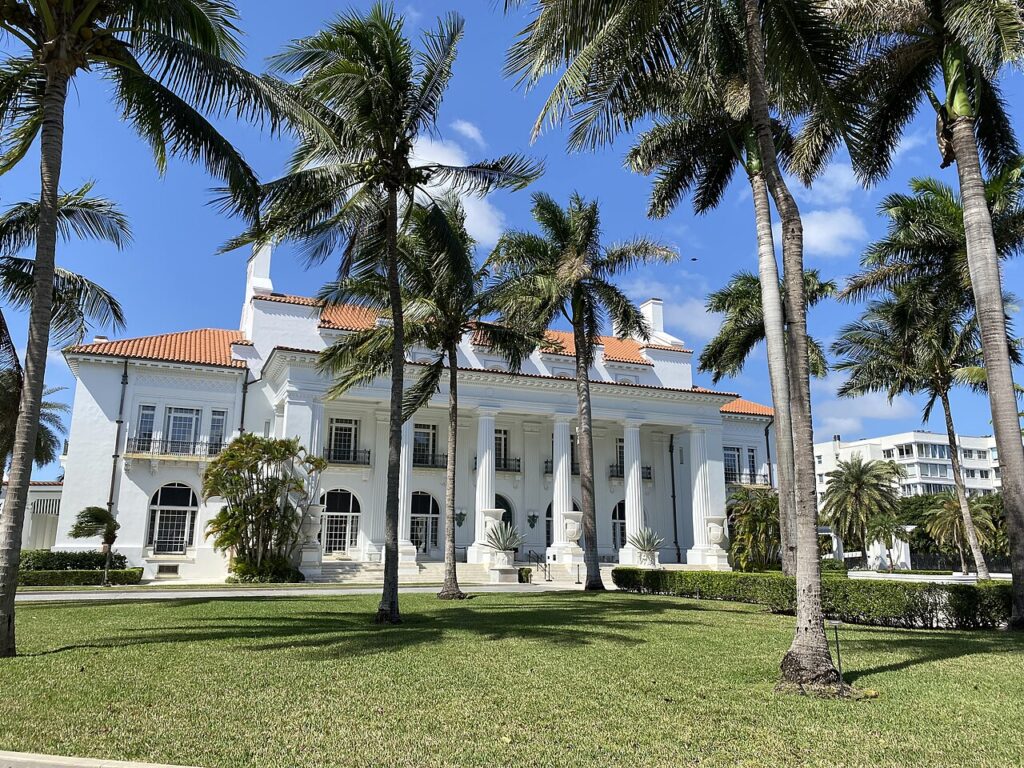 The sprawling white exterior of Whitehall surrounded by tall palm trees.