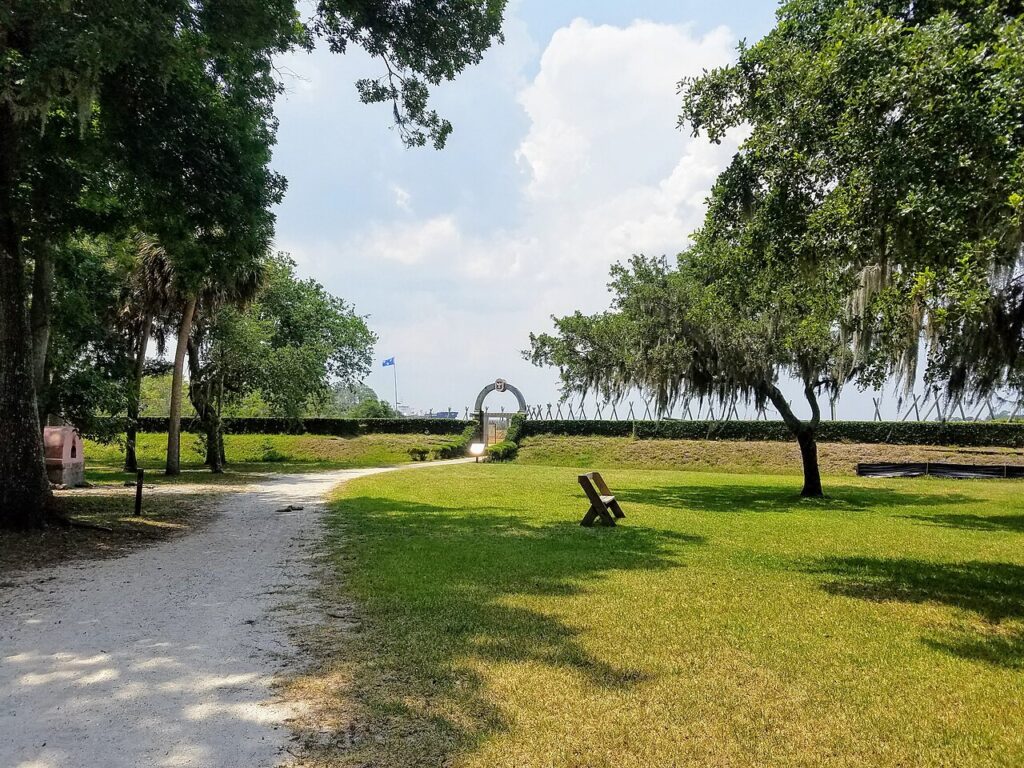 The reconstructed historical gate and earthwork walls surrounded by green trees at Fort Caroline National Memorial.